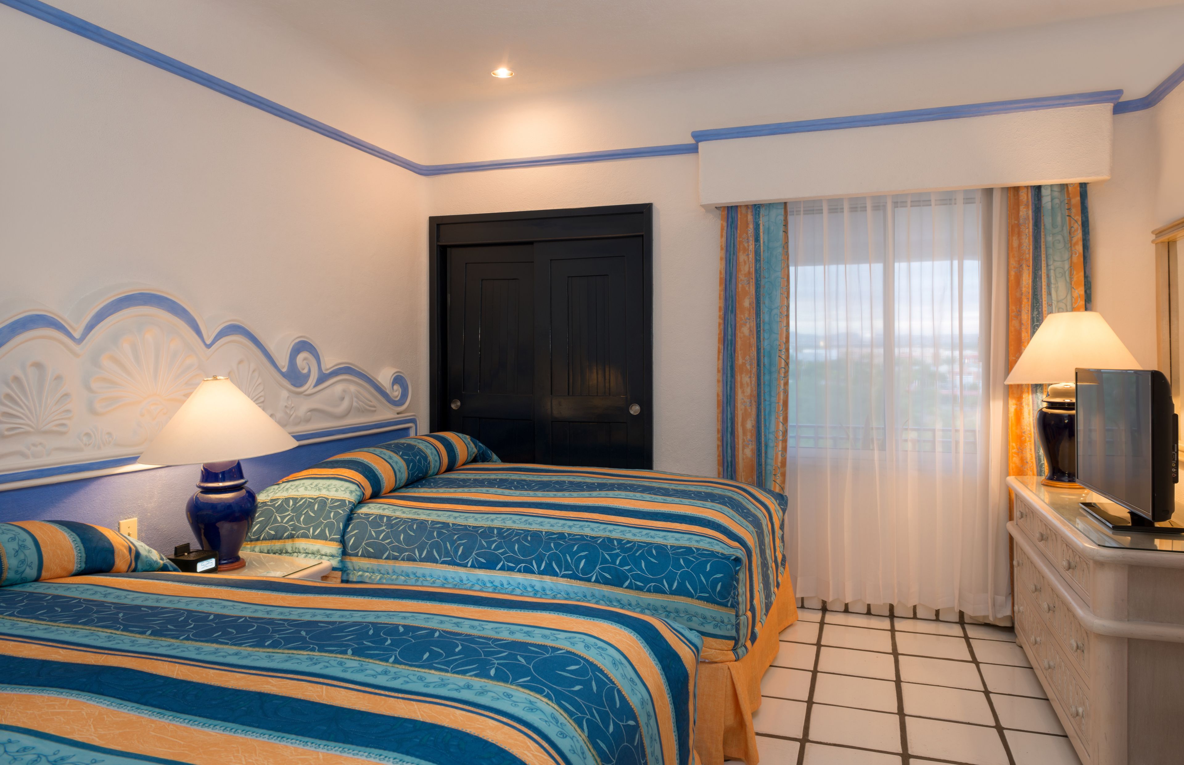 A hotel room with two beds, a TV, and a dresser.