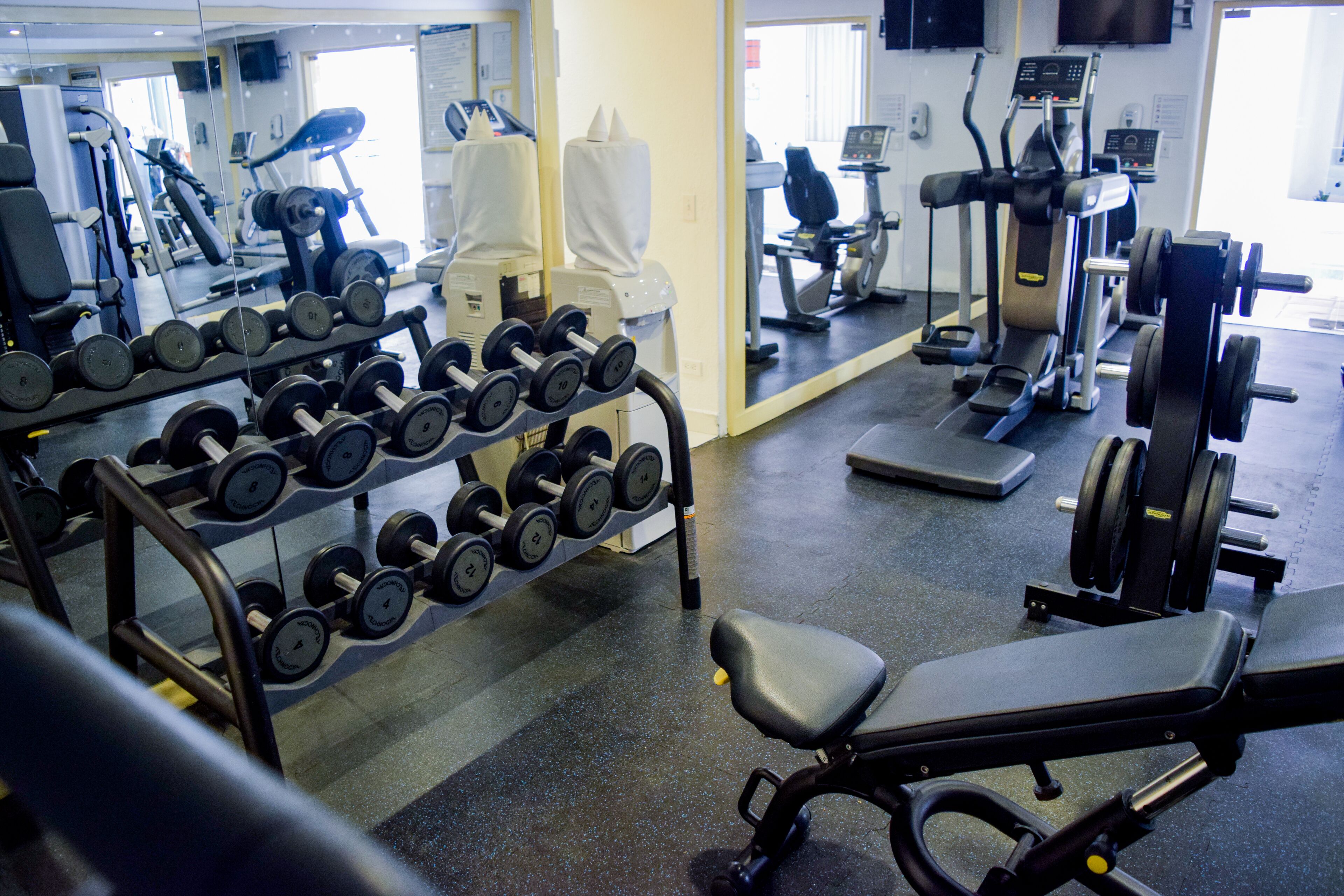 A gym with various exercise equipment including dumbbells, treadmills, and weight machines.