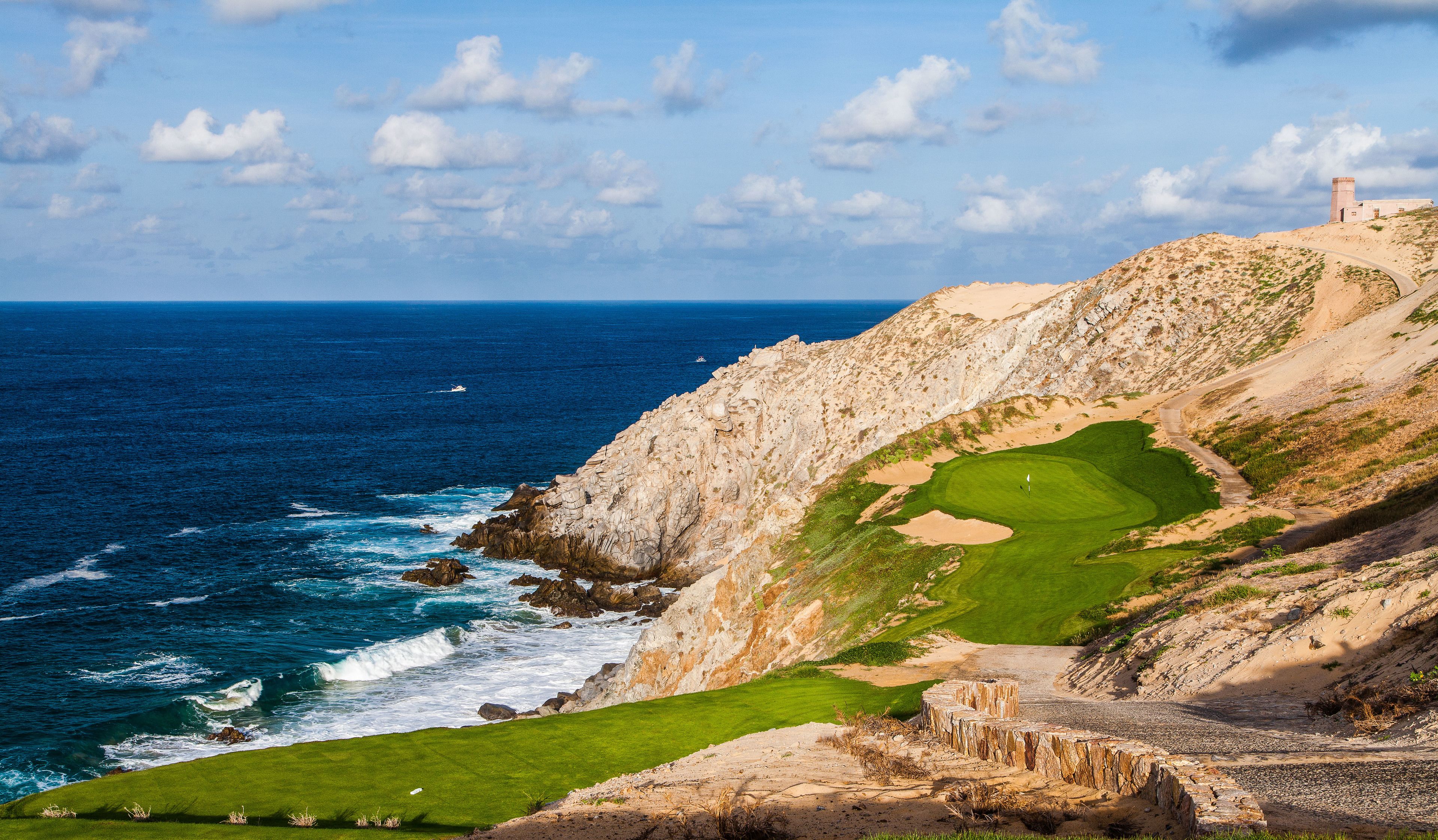 Eine Küstenlandschaft mit einem Golfplatz, felsigen Klippen und einem Leuchtturm.