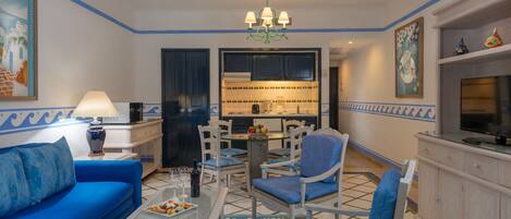 Een woonkamer met een blauwe bank, een salontafel en een eetgedeelte met stoelen en een tafel.