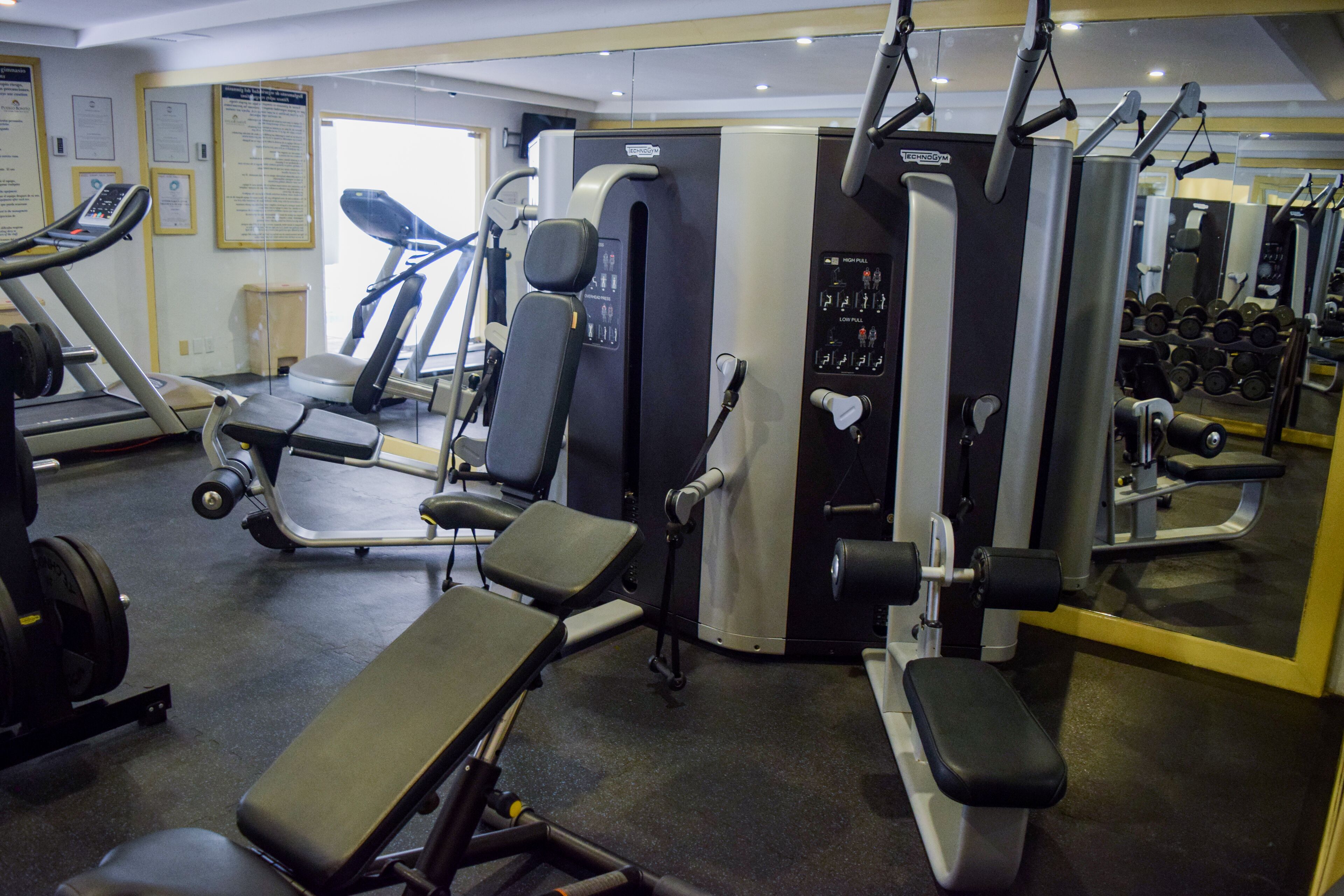 A gym with various exercise equipment including treadmills, weight machines, and free weights.