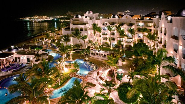 Un resort con diverse piscine, palme e vista sulla spiaggia.