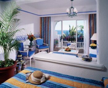 Enjoy ocean views from the balcony, featuring a comfortable bed, a sitting area with a sofa and armchairs, and a dining table. at Pueblo Bonito Los Cabos Blanco - All Inclusive