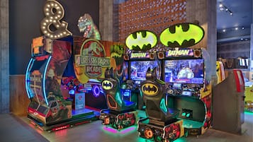 A row of arcade machines with illuminated signs, including "Jurassic Park" and "Batman" themes.