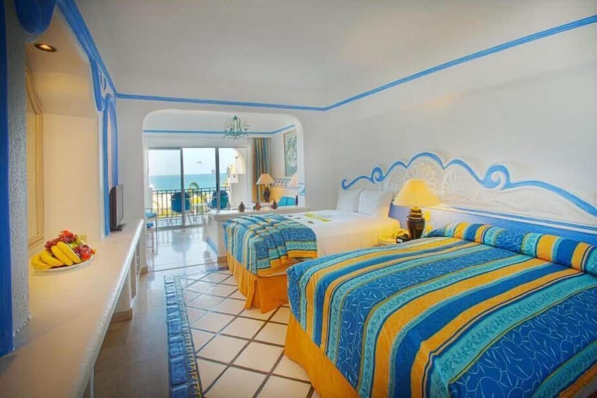 A hotel room with two beds, a balcony, and a view of the sea.