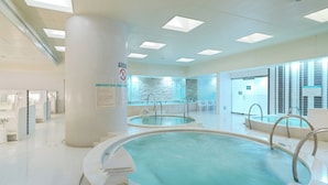 Ett modernt inomhuspoolområde med två pooler, tydlig skyltning och rökförbud.