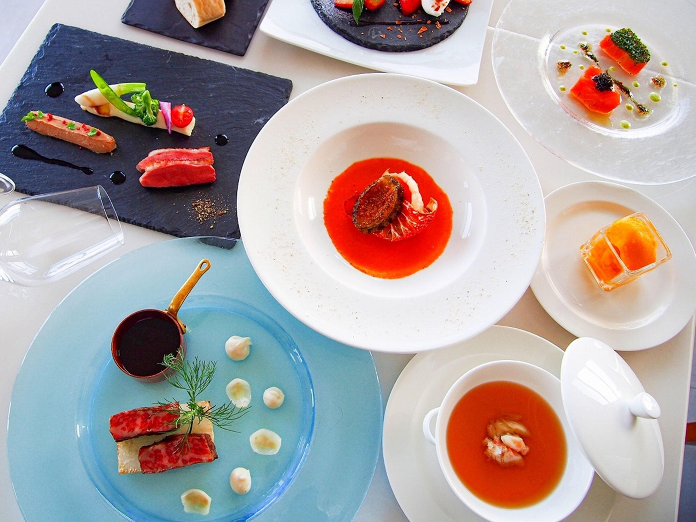 Eine Auswahl an Gerichten auf einem Tisch, darunter Meeresfrüchte, Gemüse und Desserts.