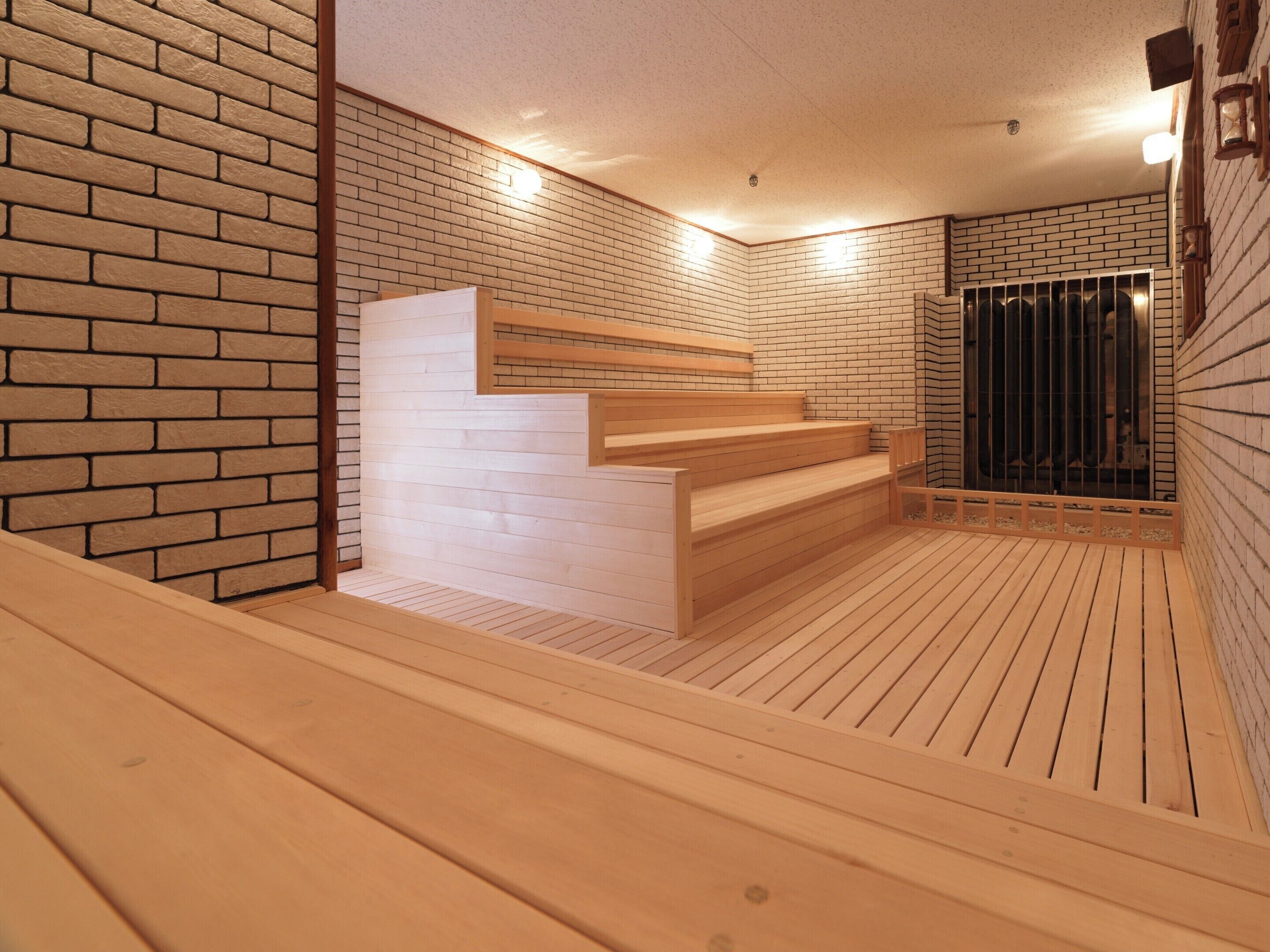 Un sauna avec des bancs en bois et un mur en briques.