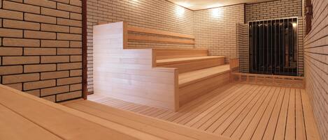 Un sauna avec des bancs en bois et un mur en briques.