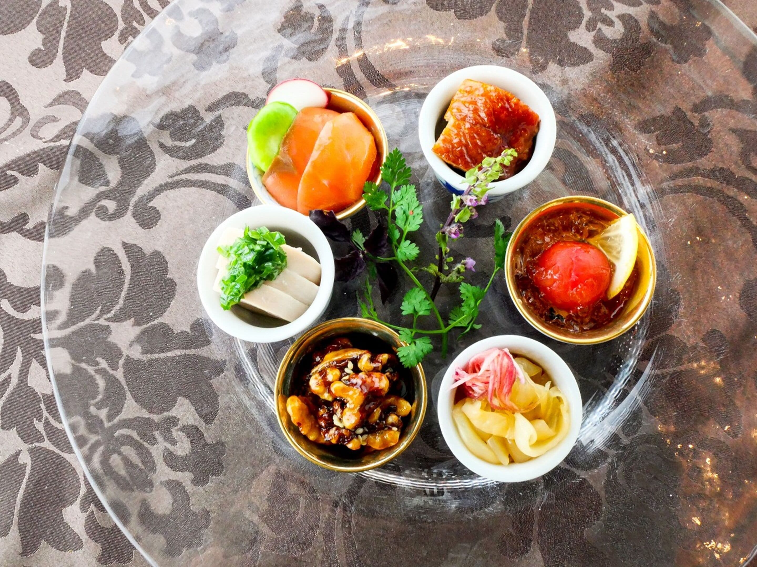 A table with various dishes including sashimi, a bowl of soup, and a dish with noodles and vegetables.