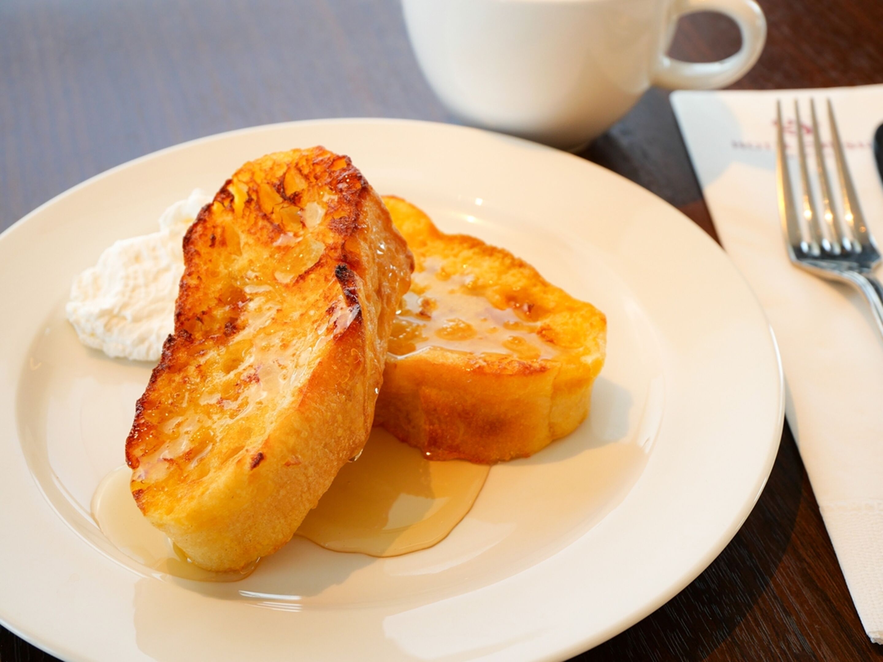 A plate with two pieces of toast and a dollop of cream on a white plate.