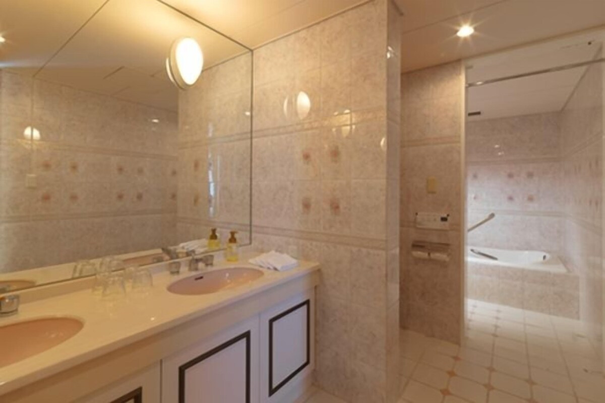 A bathroom with a large mirror, two sinks, and a bathtub.