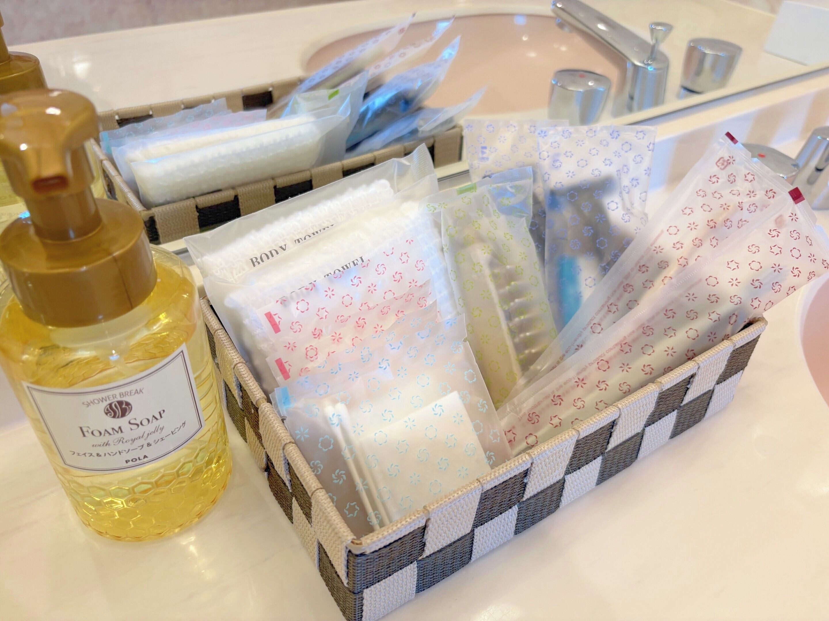 Un bagno con una bottiglia di sapone schiumogeno, un cesto di articoli da toilette e un lavandino.