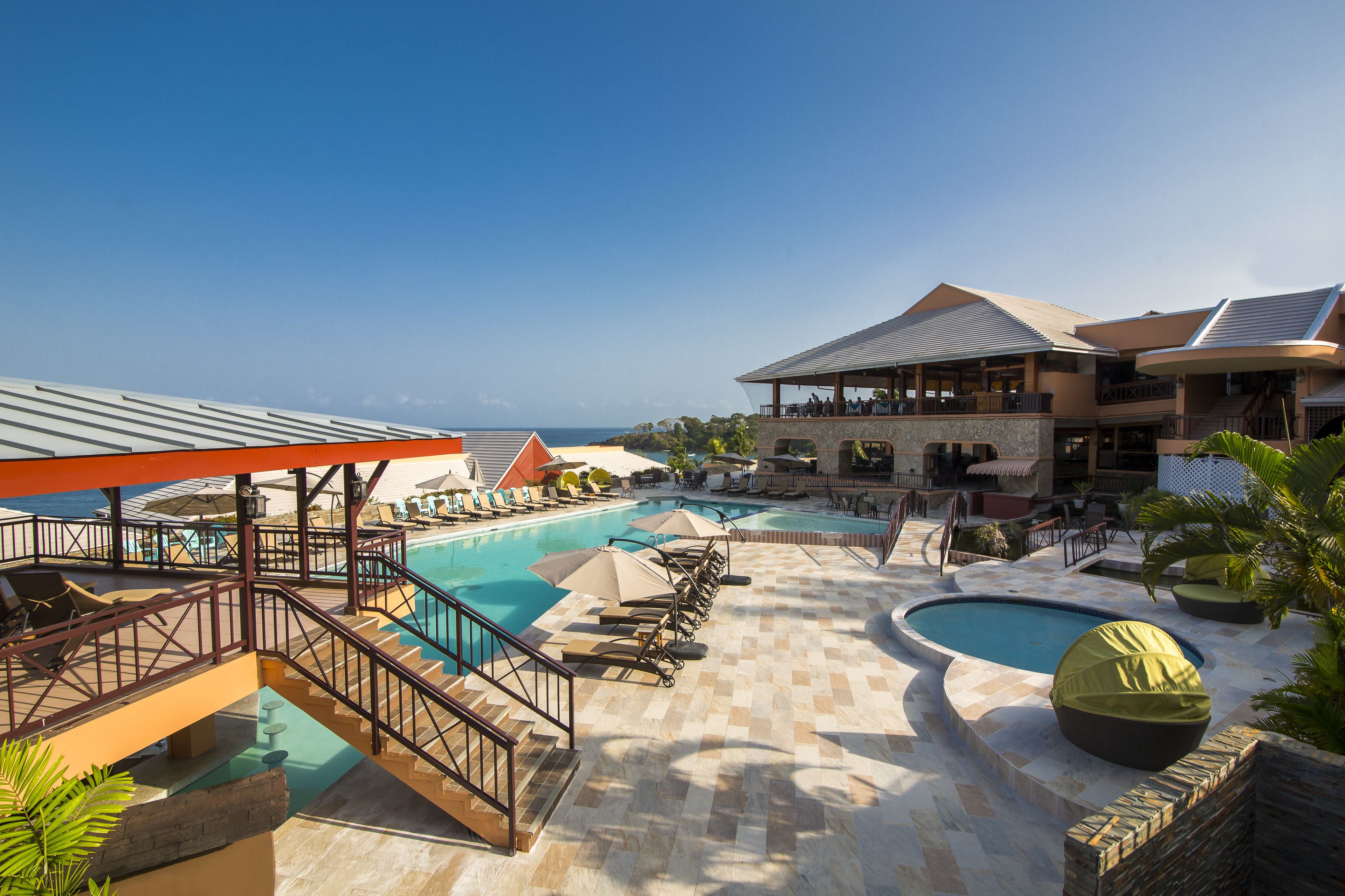 A resort with multiple swimming pools, sun loungers, and a covered area with umbrellas.