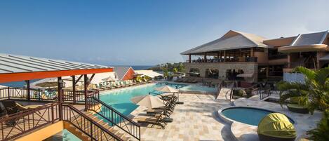 A resort with multiple swimming pools, sun loungers, and a covered area with umbrellas.