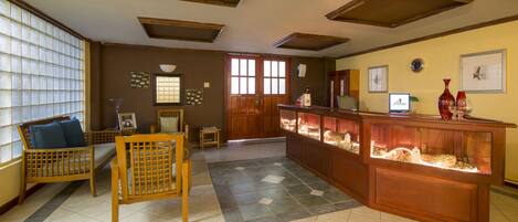 Un interior tradicional con muebles de madera, piso de baldosas y una vitrina con objetos.
