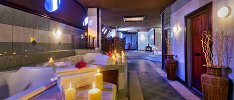 Zona de spa con mostrador de recepción, velas y un área de recepción con una puerta roja.
