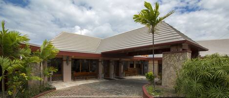 A building with a stone facade, a covered entrance, and a paved courtyard.