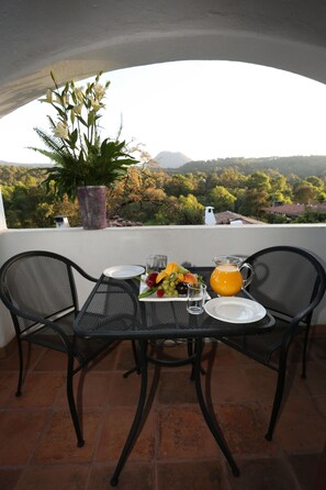 A terrace with a table set for breakfast, a potted plant, and a scenic view of hills and trees. - Hotel Avandaro Golf And Spa (Valle de Bravo)