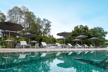 Una piscina al aire libre, sombrillas, sillones reclinables de piscina