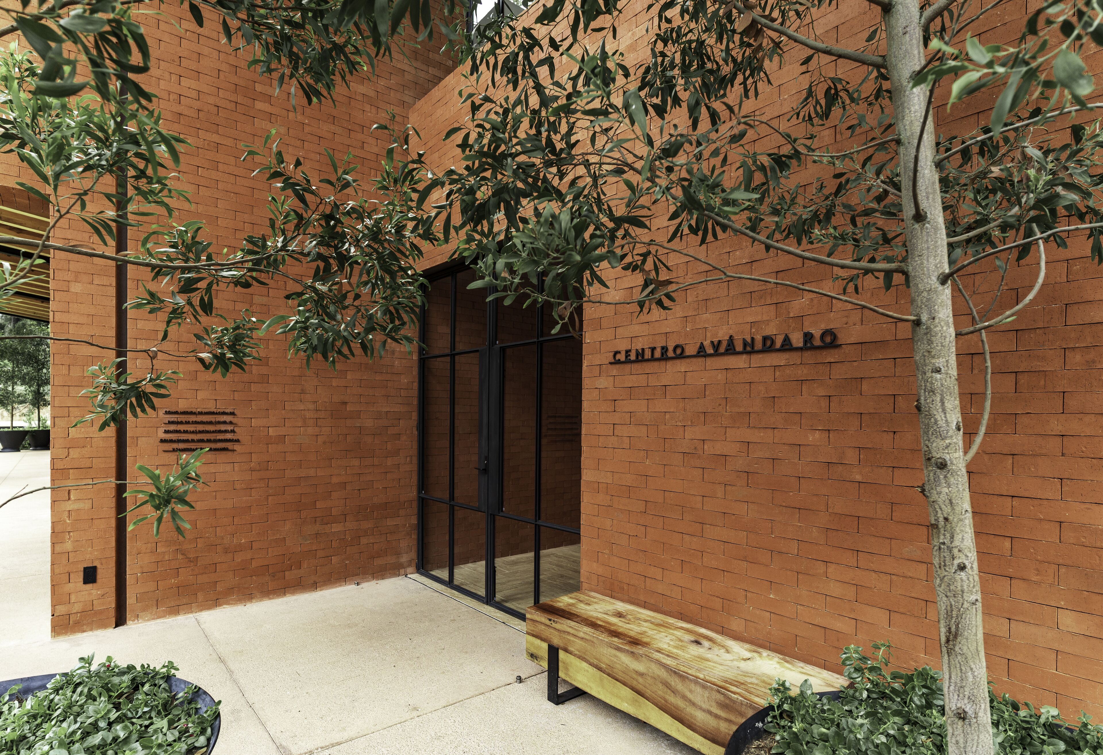 Un edificio de ladrillo con un banco de madera y una puerta.