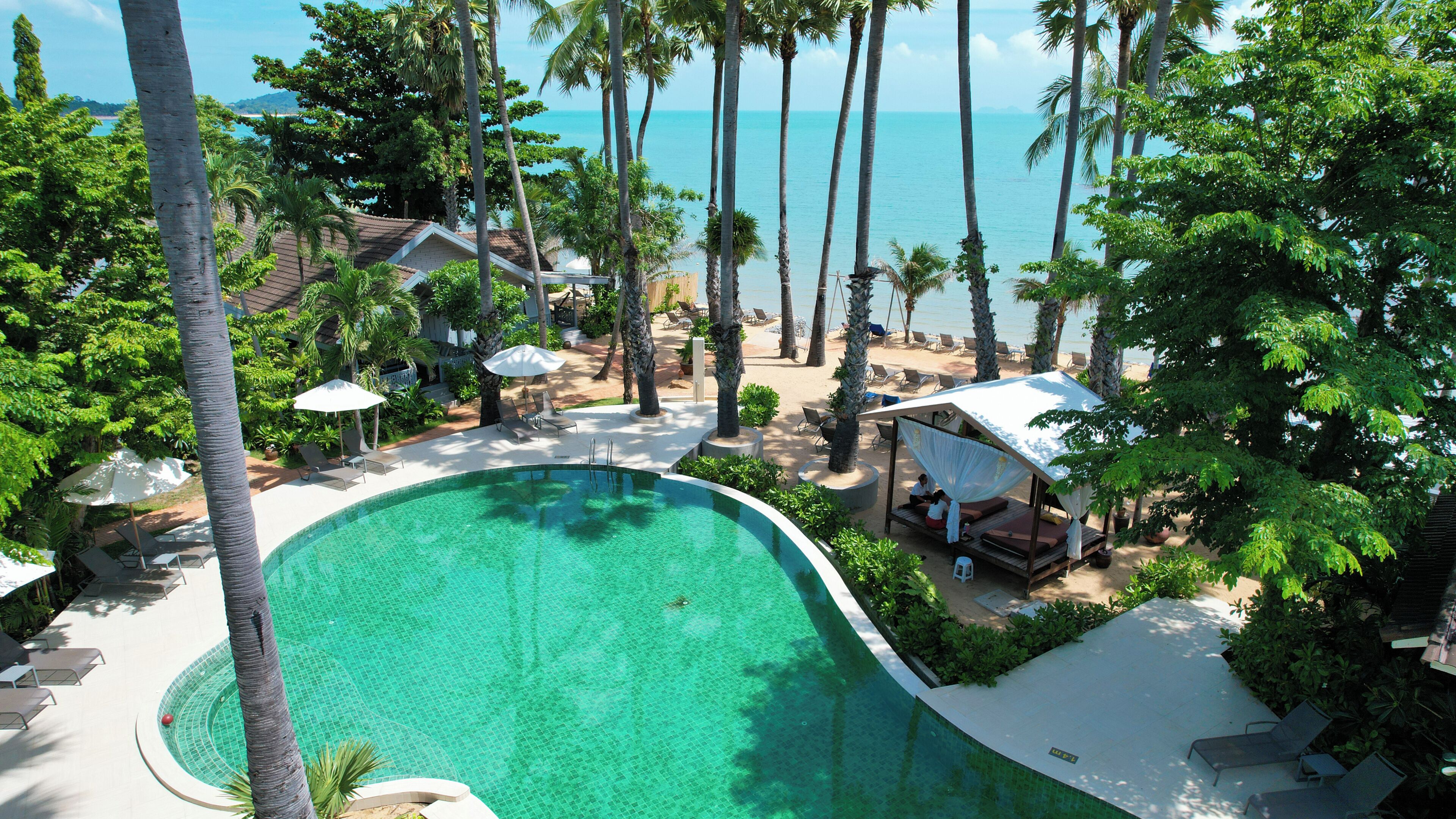 Un resort con piscina, palmeras y zona de playa.