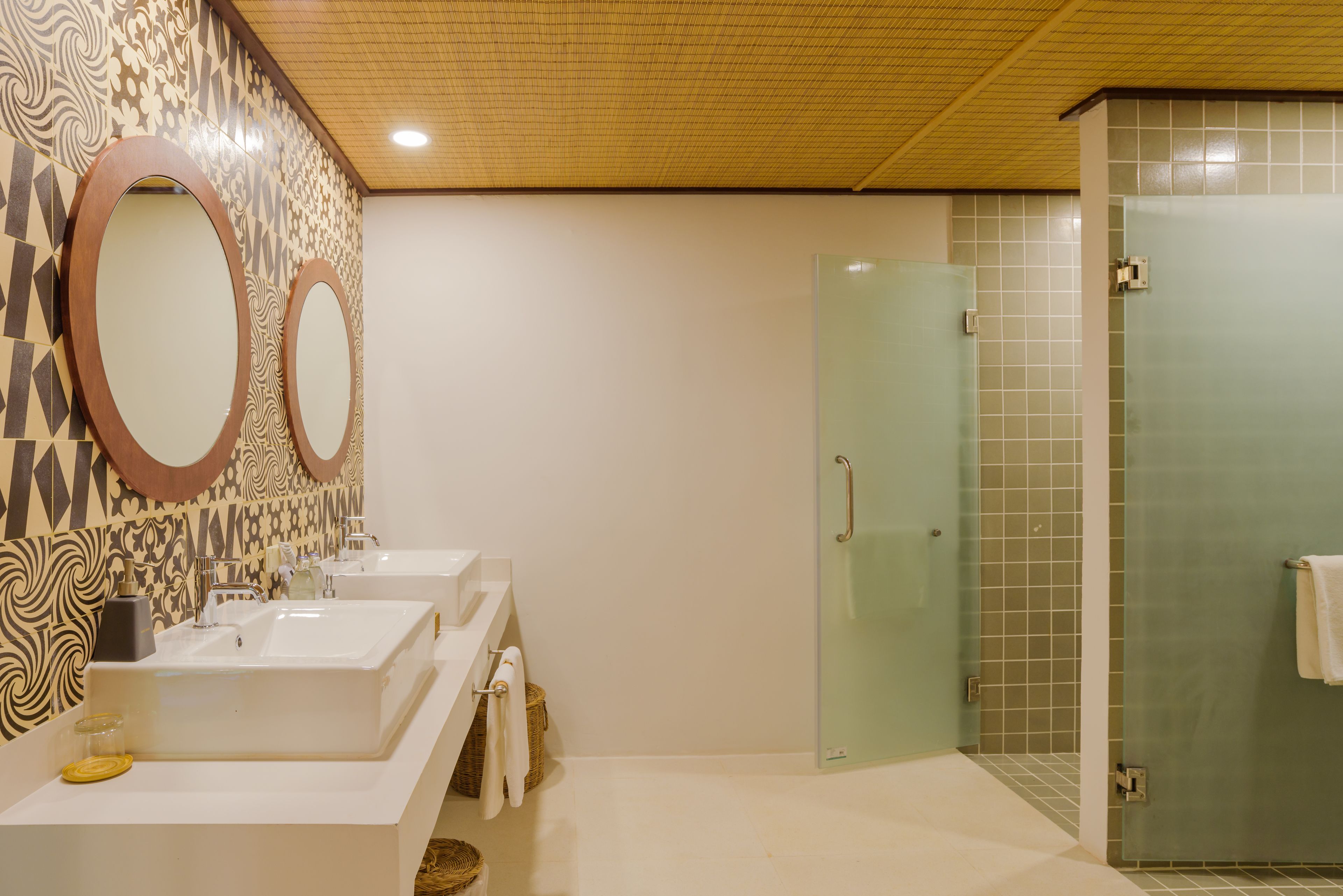 Une salle de bain avec deux lavabos, une porte de douche en verre et des carreaux muraux à motifs.