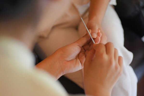 A close-up of a person holding a child's hand, possibly in a medical or caregiving setting.