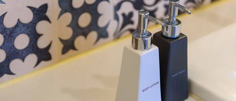 Two hand soap dispensers on a bathroom counter with a patterned tile backsplash.