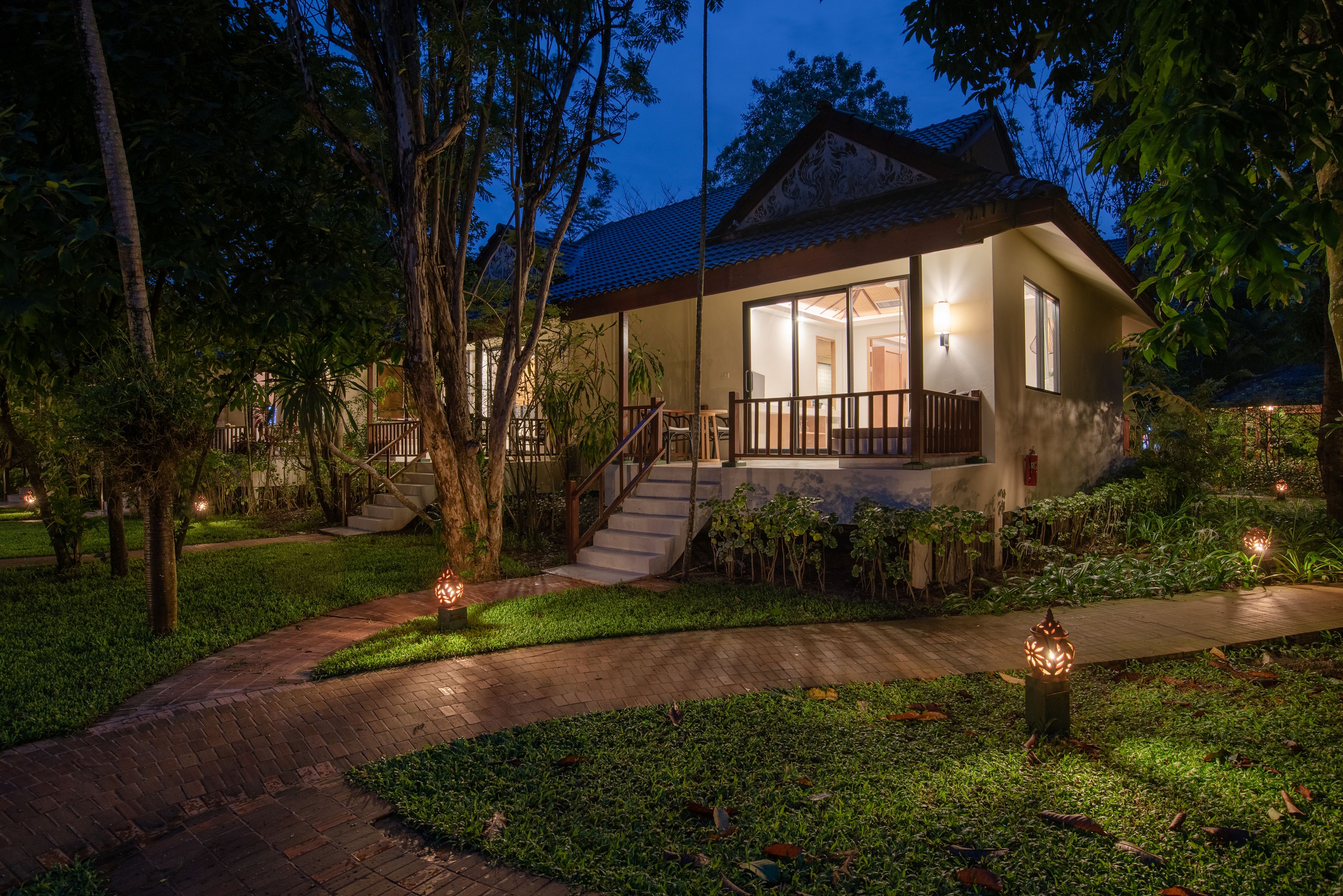 A two-story house with a covered porch, a staircase, and a garden with pathways.
