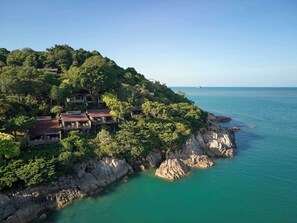 A coastal property with multiple buildings surrounded by lush greenery and rocky terrain. - Garrya Tongsai Bay Samui (Koh Samui)