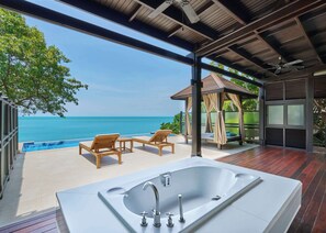 A modern outdoor bathroom with a large bathtub, wooden lounge chairs, and a view of the ocean. - Garrya Tongsai Bay Samui (Koh Samui)