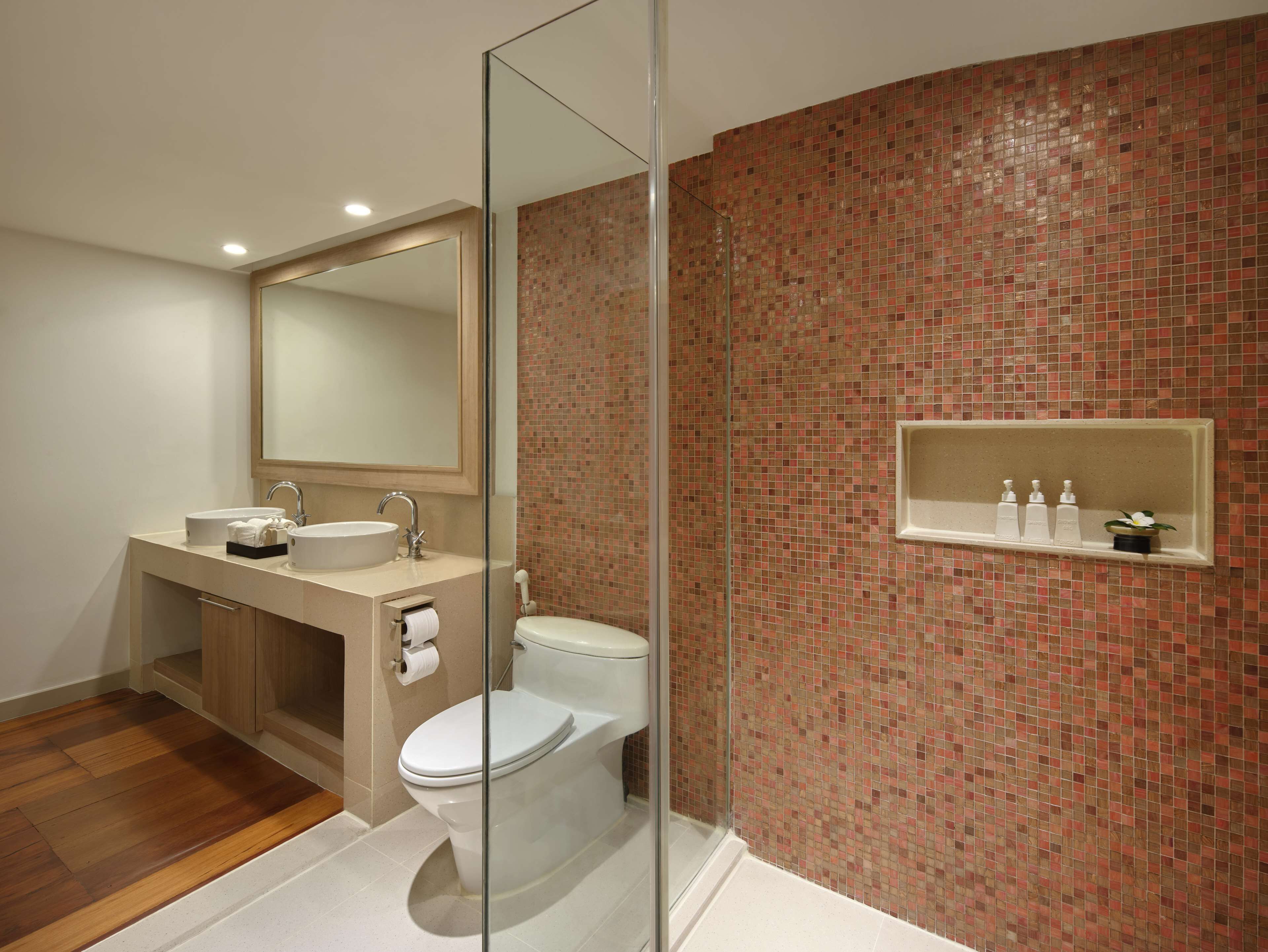 Een moderne badkamer met een douchecabine van glas, een wastafel met spiegel en een toilet.