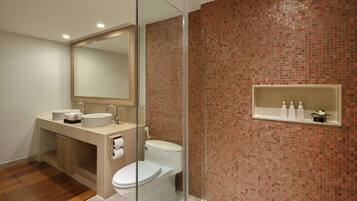 Een moderne badkamer met een douchecabine van glas, een wastafel met spiegel en een toilet.