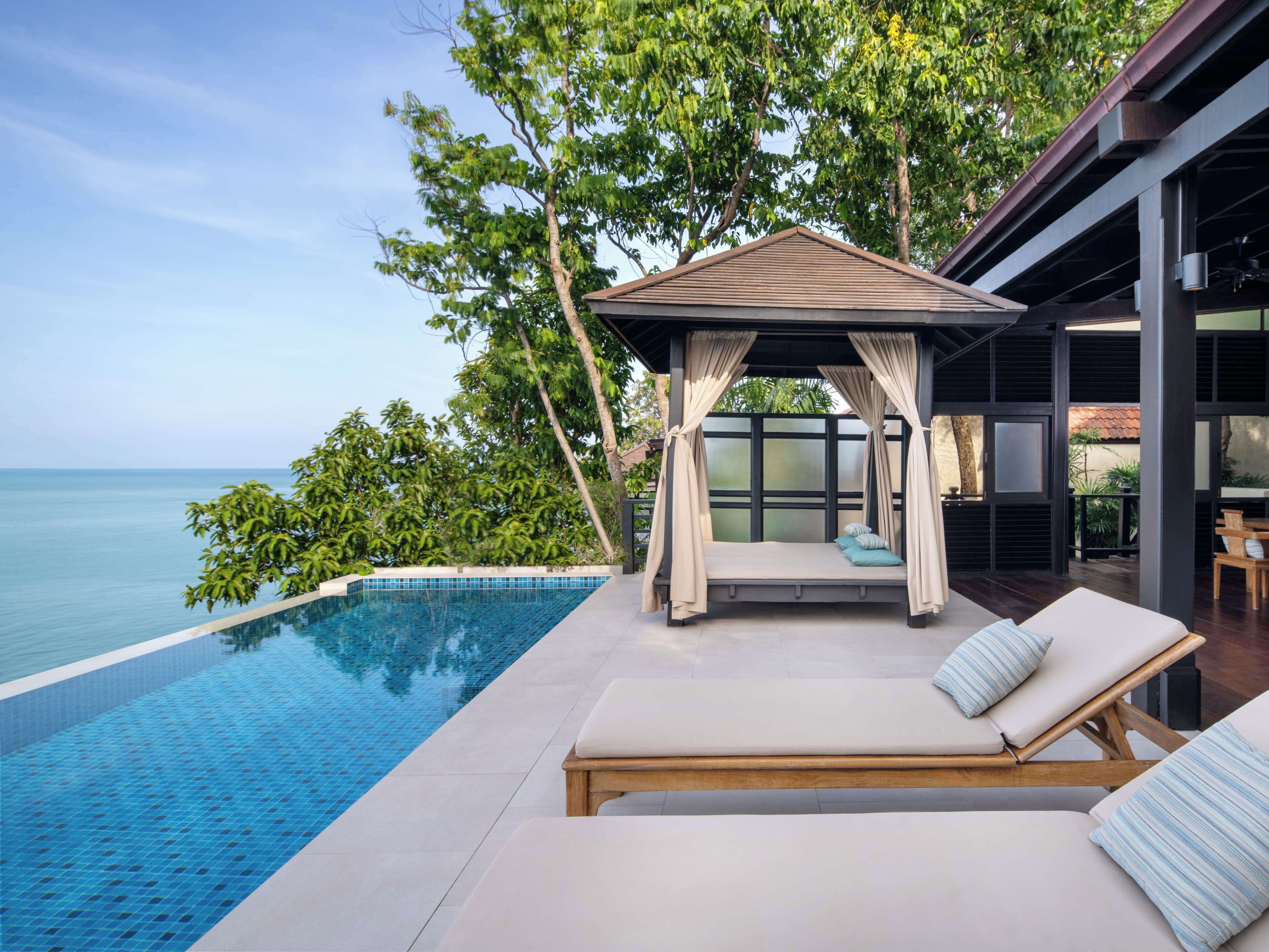 A private pool area with a wooden deck, a covered seating area, and a view of the sea.