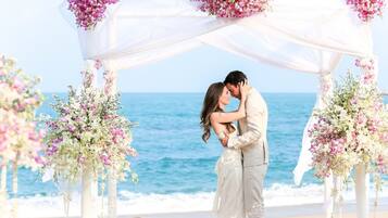 Couples can exchange vows in a serene coastal setting, surrounded by a beautiful floral canopy.