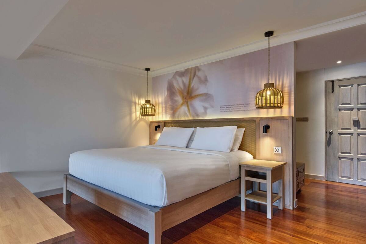 A neatly arranged bedroom with a wooden bed, bedside tables, and a wall-mounted light fixture.