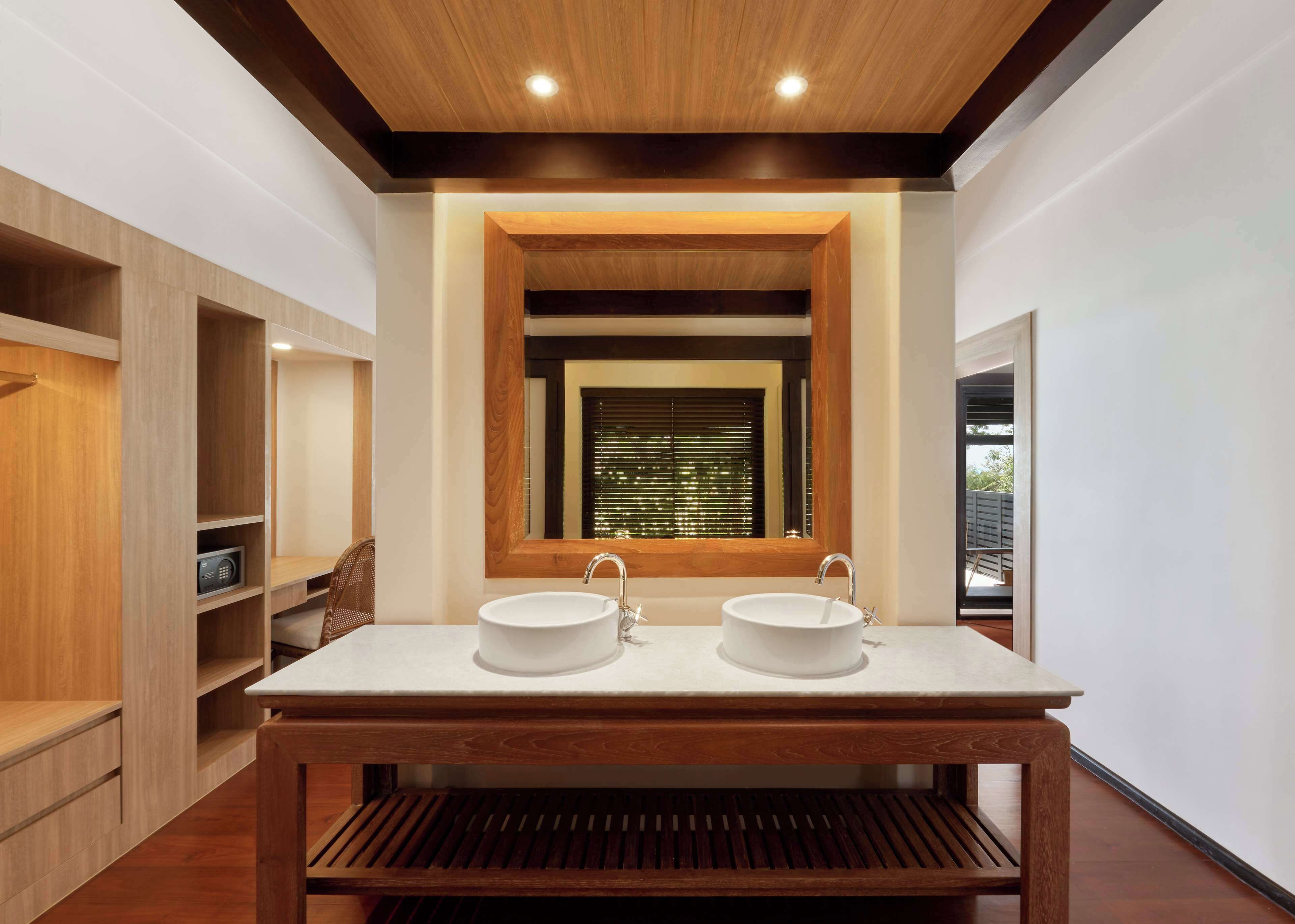A modern bathroom with a wooden vanity, two sinks, and a large mirror.