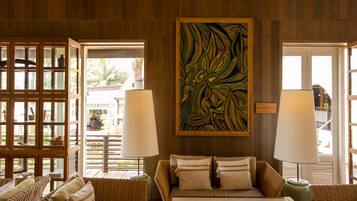 A room with wicker furniture, a large abstract painting, and two lamps.