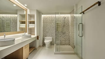 A modern bathroom with a large mirror, two sinks, a toilet, and a glass-enclosed shower.
