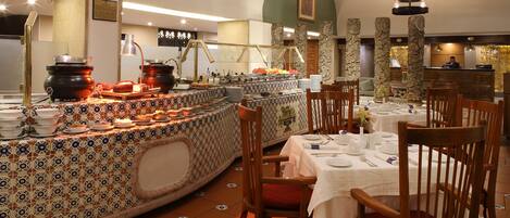 Un restaurante con servicio de buffet, que ofrece una variedad de platos y una barra con ollas de cocina.