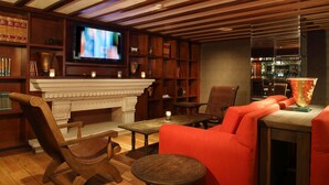 Una biblioteca acogedora con chimenea, estanterías y asientos cómodos.