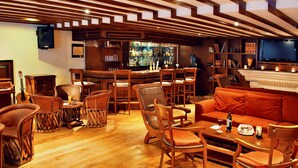 Una zona de bar con muebles de madera, un televisor y una estantería.