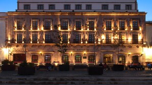 Un edificio histórico con fachada clásica, varios balcones y acceso a nivel de calle.