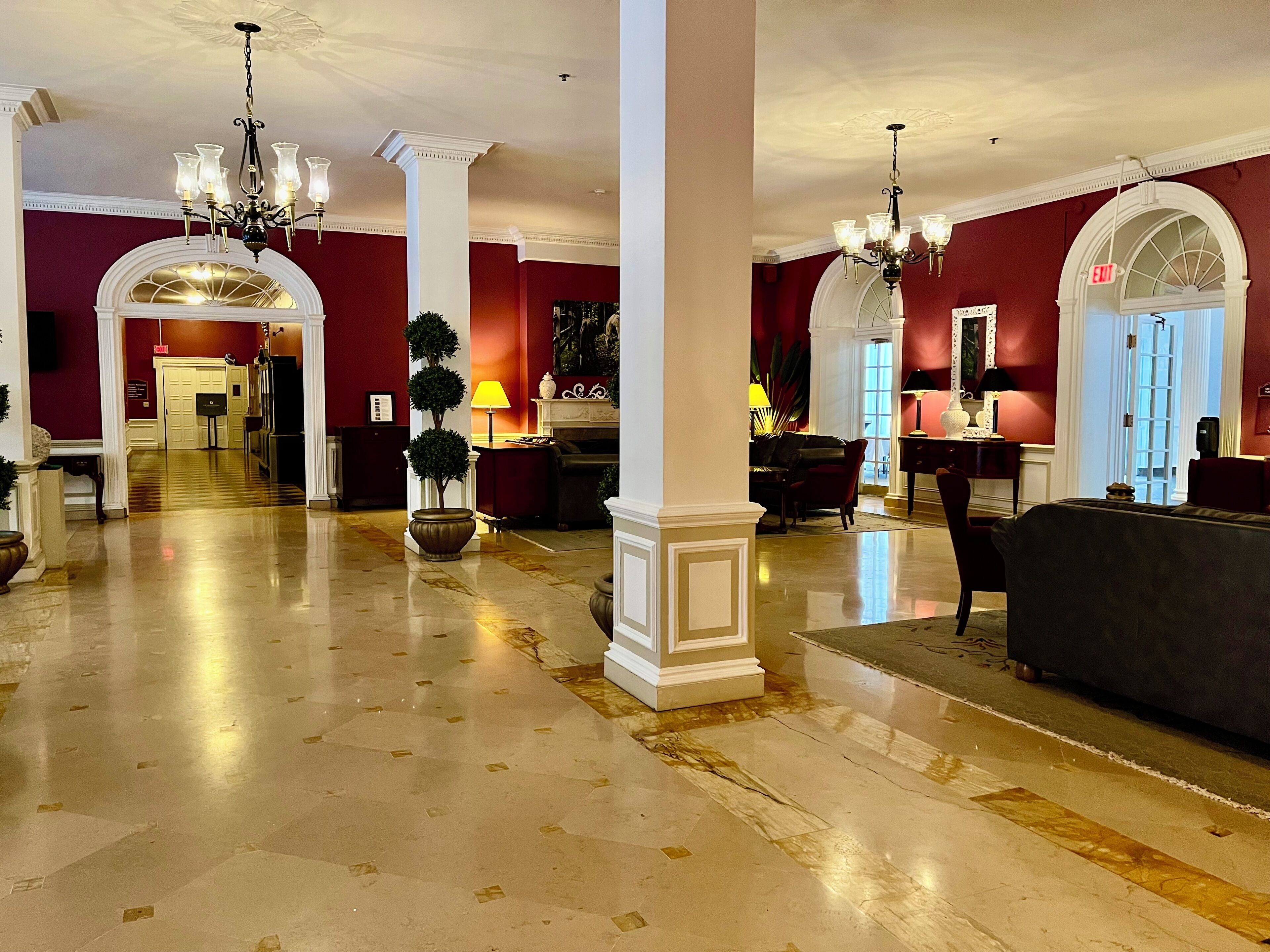 A grand lobby with marble floors, a chandelier, and a reception desk.