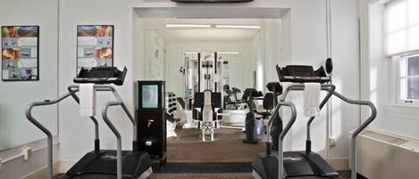 Une salle de sport équipée de tapis de course, d’un téléviseur et d’appareils d’exercice.
