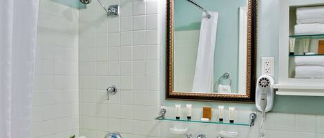 A bathroom with a bathtub, a sink, a toilet, a mirror, and a shower area.