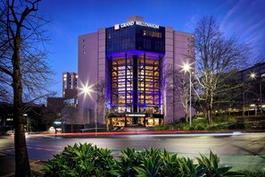 A modern hotel with a prominent "Grand Millennium" sign, featuring a glass facade and illuminated blue lighting. - Grand Millennium Auckland (Auckland)