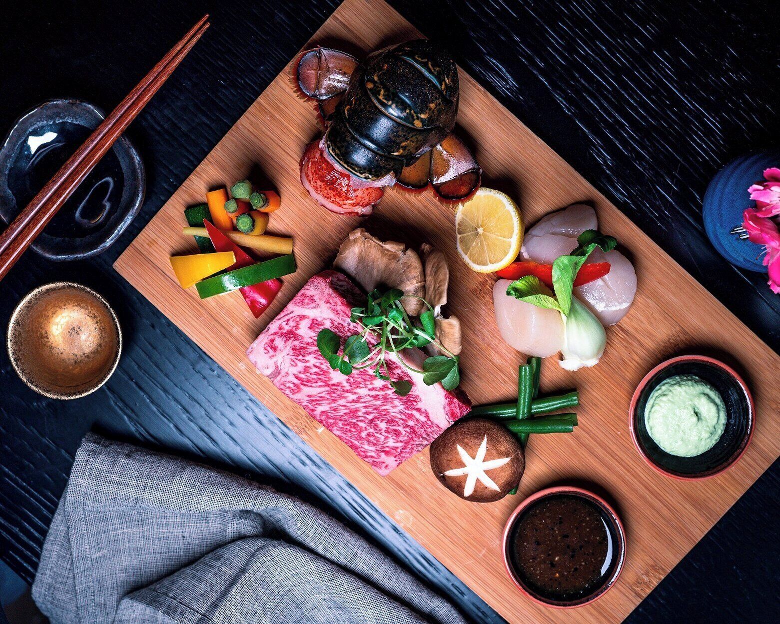 A wooden board with various food items including meat, vegetables, and condiments.
