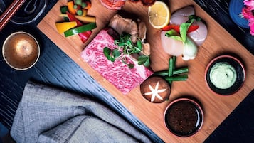 A wooden board with various food items including meat, vegetables, and condiments.